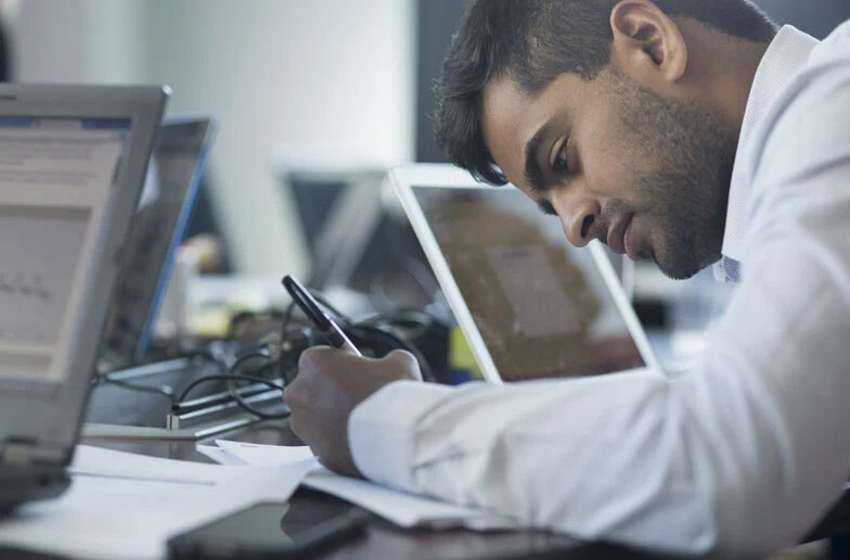 Three people sitting together at a table in a conference room.